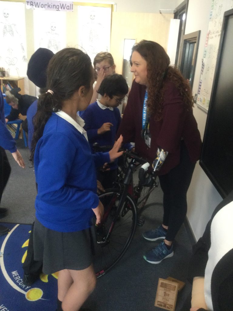 A small group of students are pictured observing a bicycle with Para-Triathlete, Tammy Pullen.
