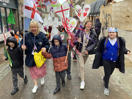 A photo showing a small group of students and staff dressed up in their winter coats, leading a parade for St. George's Day.