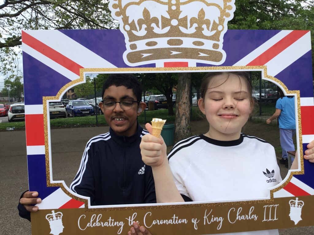 A photo of two pupils celebrating the King's Coronation in May 2023, posing for the camera in a decorative frame to mark the occasion.
