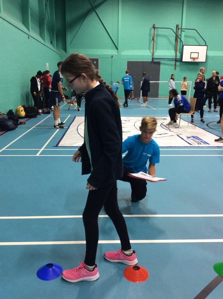 A female student is pictured participating in an activity in the Sports Hall, as part of a school-wide competition.