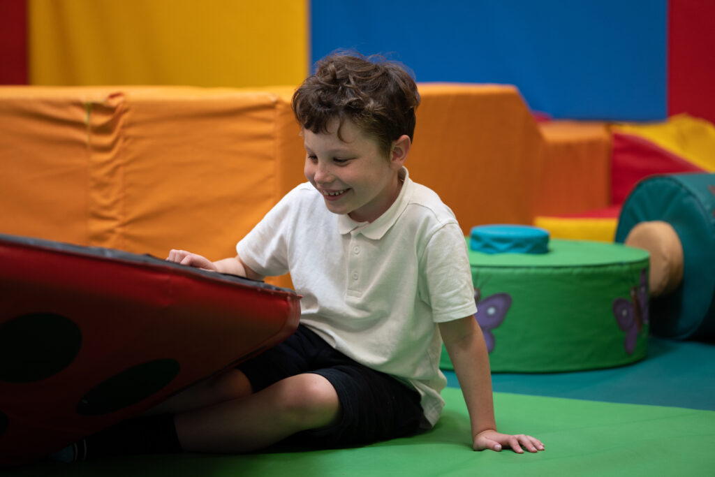 A young boy in a soft play area smiling