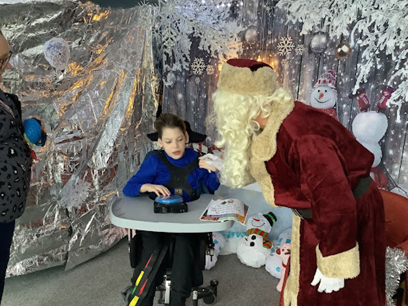A student at Milestone Academy receives a visit from Father Christmas in his grotto.