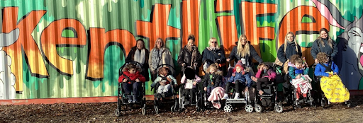 Staff and parents are pictured posing for a photo together, alongside students in wheelchairs during a trip to Kent Life Farm Park in Maidstone, Kent.