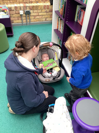 A young pupil is seen interacting with his baby brother and mother who have come to join him during a Reading Brunch session.